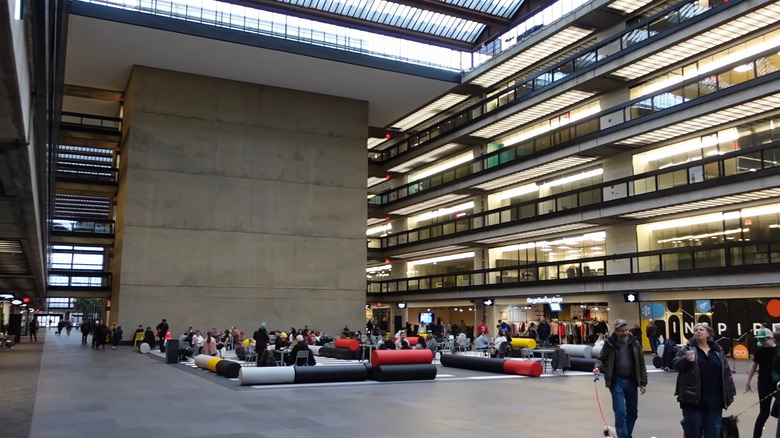 a wide office lobby with colorful chairs centered around a wide concrete pillar