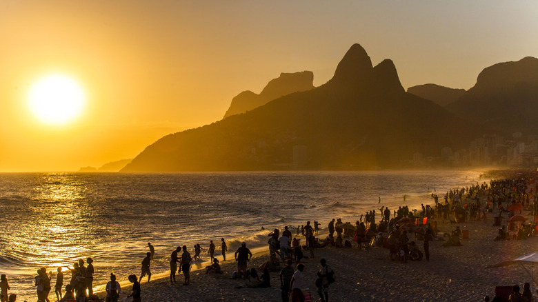 Ipanema beach lined with people at sunset in Brazil