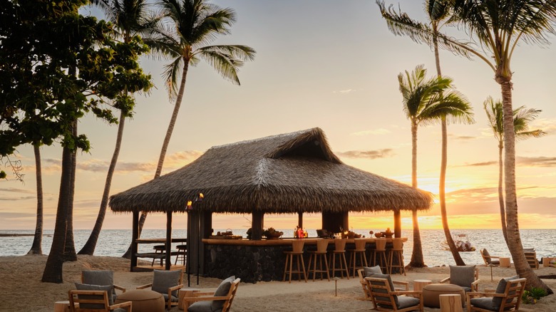 Thatched roof bar with sunset and ocean in background