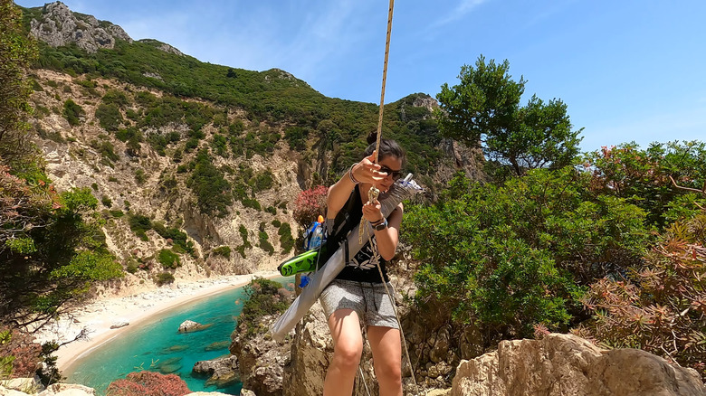 woman climbing down rope to beach