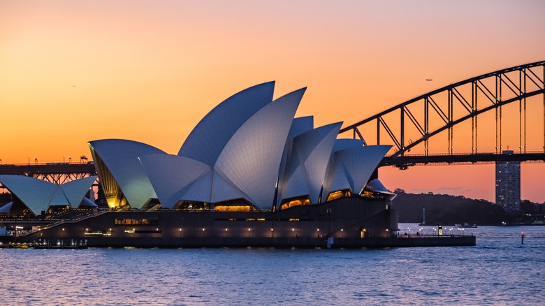 Sydney Opera House at sunset with Sydney Harbour Bridge in the background.