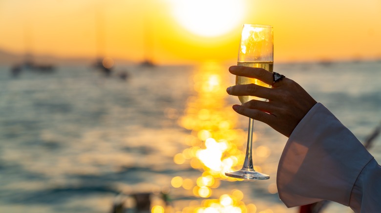 Woman's holding wine glass at sunset