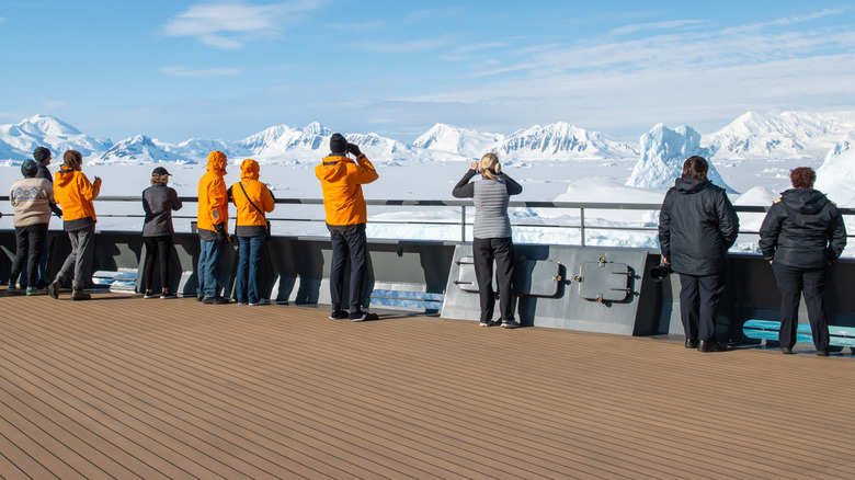 People standing on a boat, looking at the snowy peaks of Antarctica