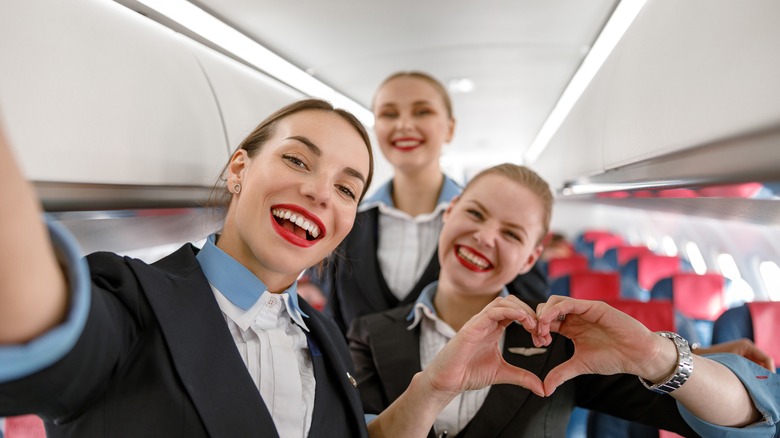 Smiling flight attendants taking photo on a plane