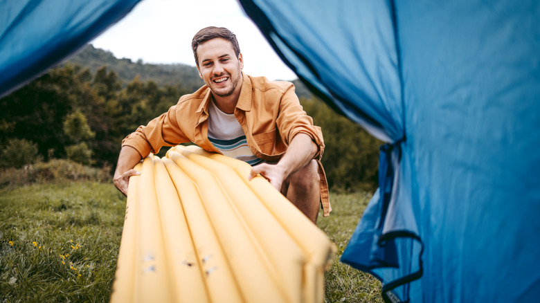 Man puts air mattress into tent