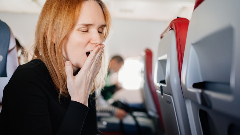 A woman yawning in a plane