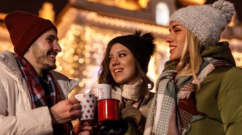 Friends enjoying gluhwein at a Christmas market on a winter evening