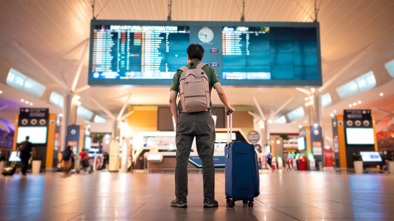 Traveler getting looking at departure/arrival screen in airport