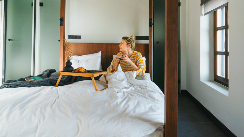 A woman eating on a hotel room bed