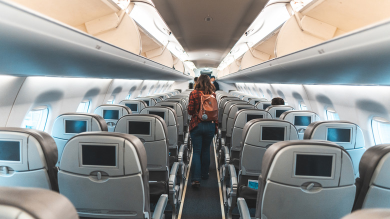 Person walking down the aisle of a plane after a flight