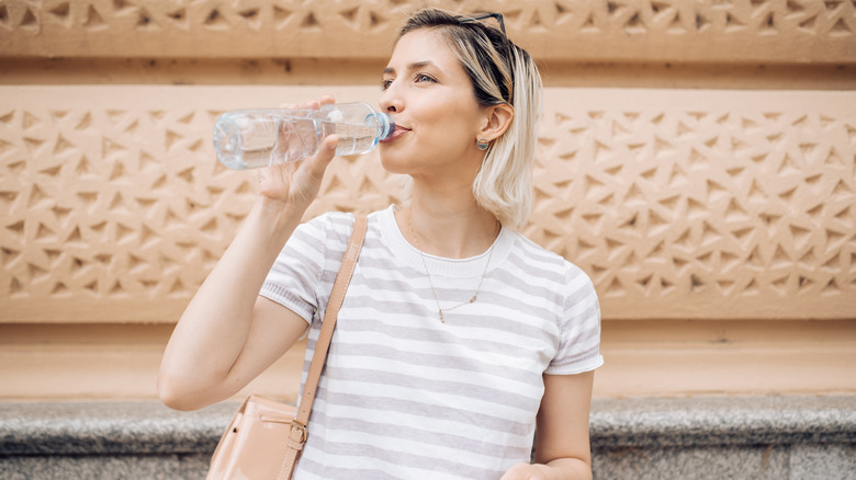 Woman drinking from plastic water bottle