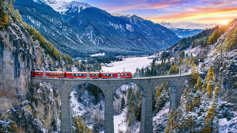 Train emerging from a tunnel at sunset in the Alps