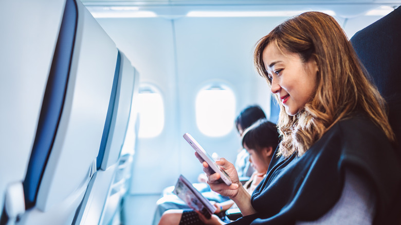 Woman using phone on airplane