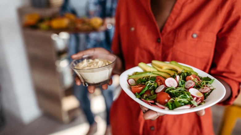 A woman carrying two plates of food.