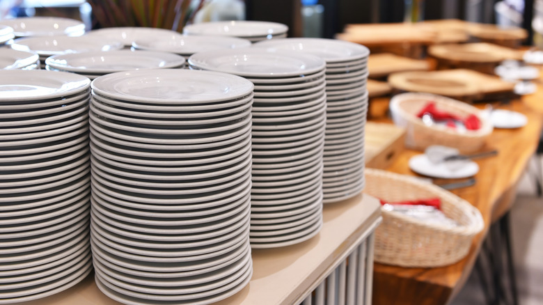 Stacks of white plates at a buffet.