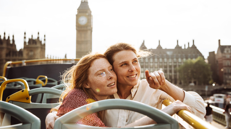 A couple on vacation together taking a tour of London and pointing