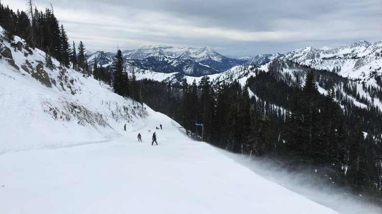 Snowy mountains with people skiing down a slope.