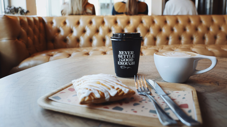 pastry on wooden tray with ceramic mug and black coffee cup