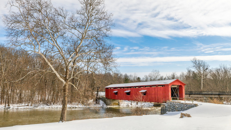 Red covered bridge in Indiana with snow and bare trees