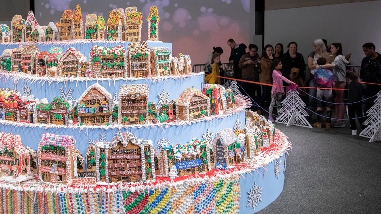 tourists line up behind multiple-storied gingerbread village display