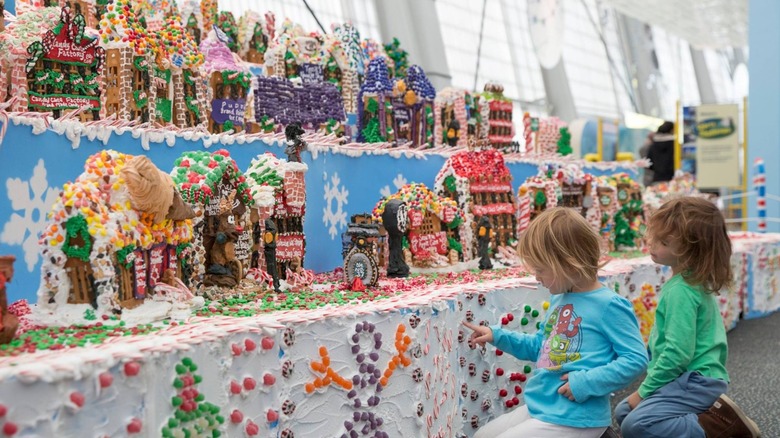 Kids kneel down and examine gingerbread village display