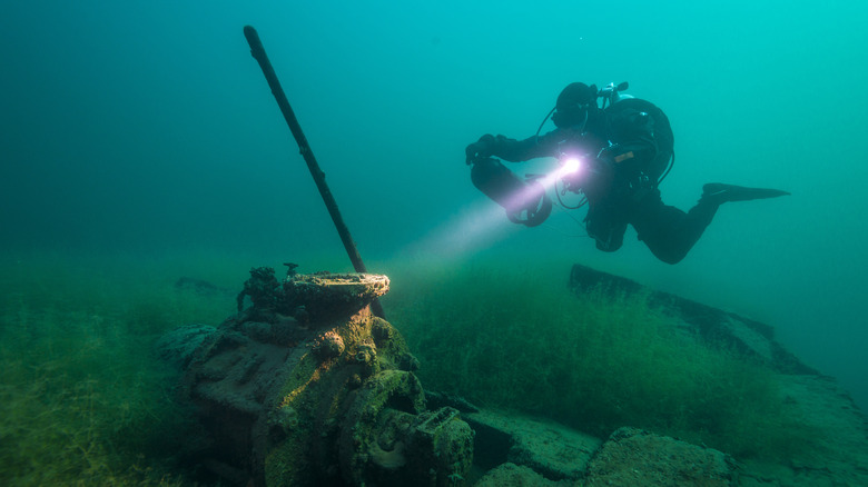 Diver examining old machinery underwater