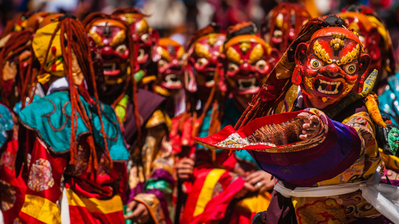 Bhutan performers dressed in vibrant yellow and red costumes wearing animal-like masks