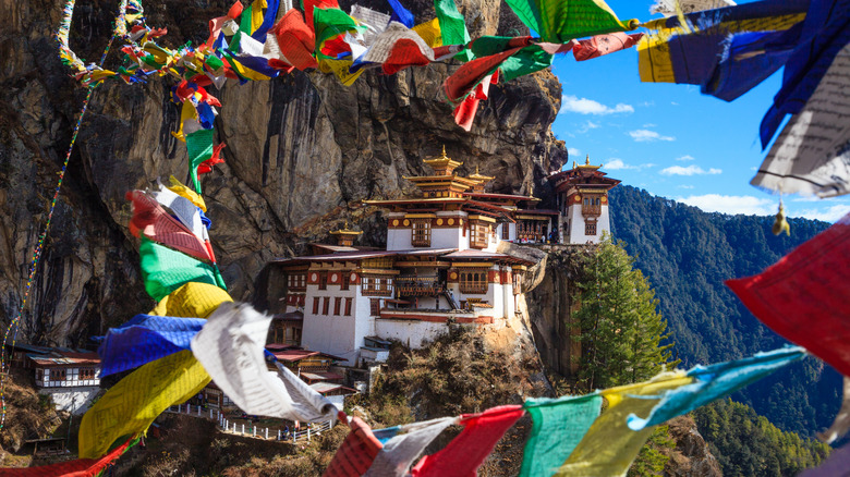 A mountainside temple framed by colorful flags in Bhutan