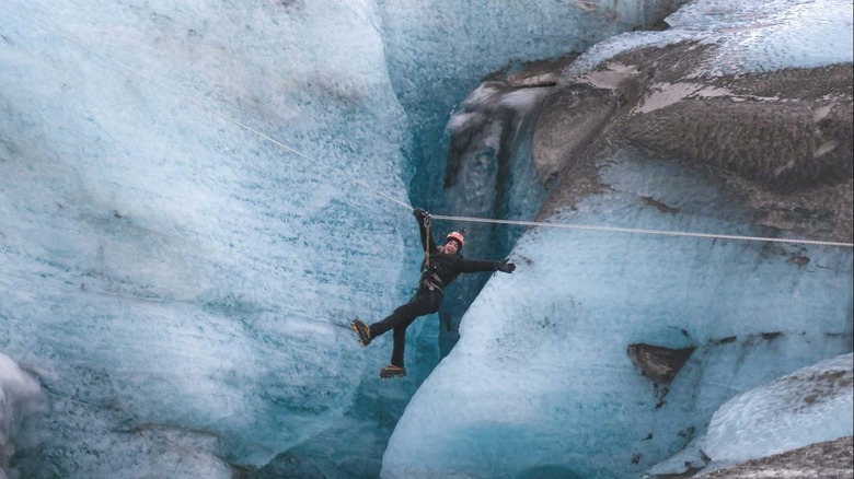 a woman smiles while flying over a glacier zip line