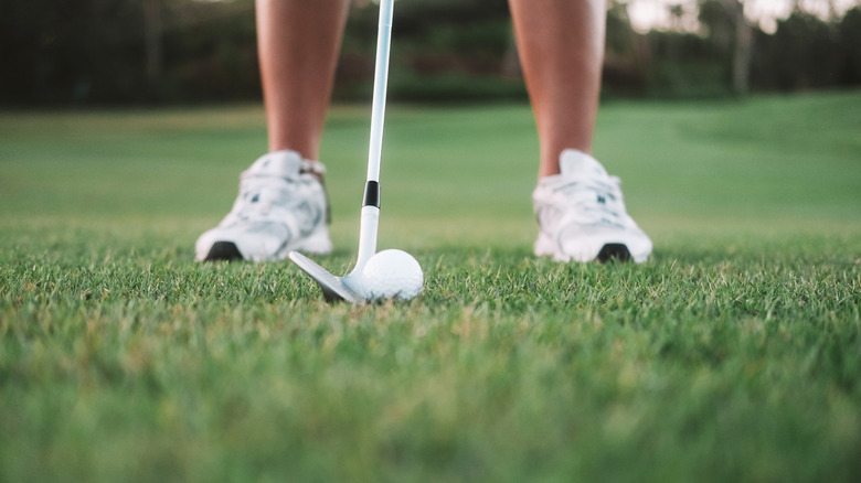 Close-up of person's legs and club with golf ball