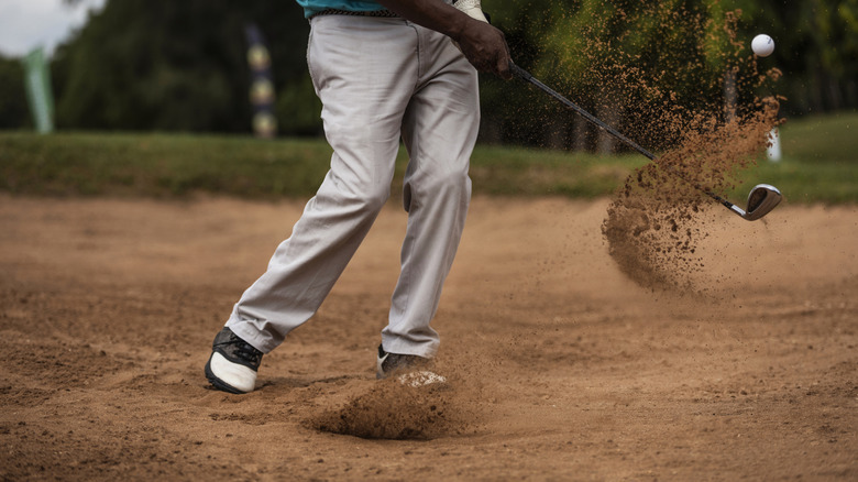 golfer hitting ball on dirt