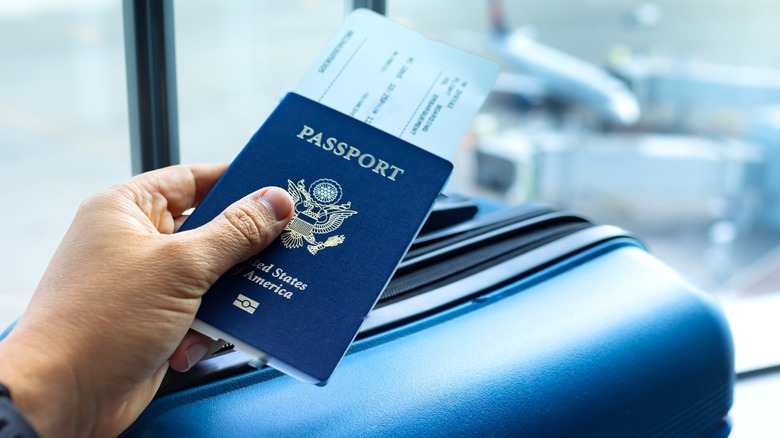 Person holding a passport over a suitcase