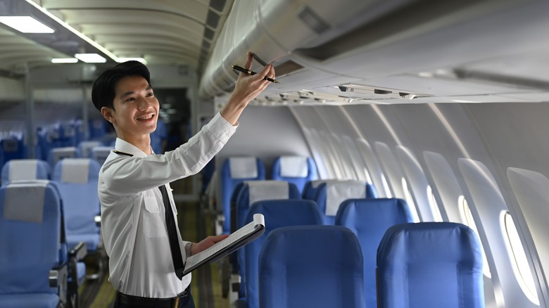 Flight attendant checks plane overhead bins