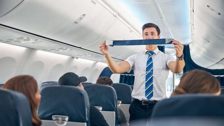 Flight attendant demonstrating seatbelt safety