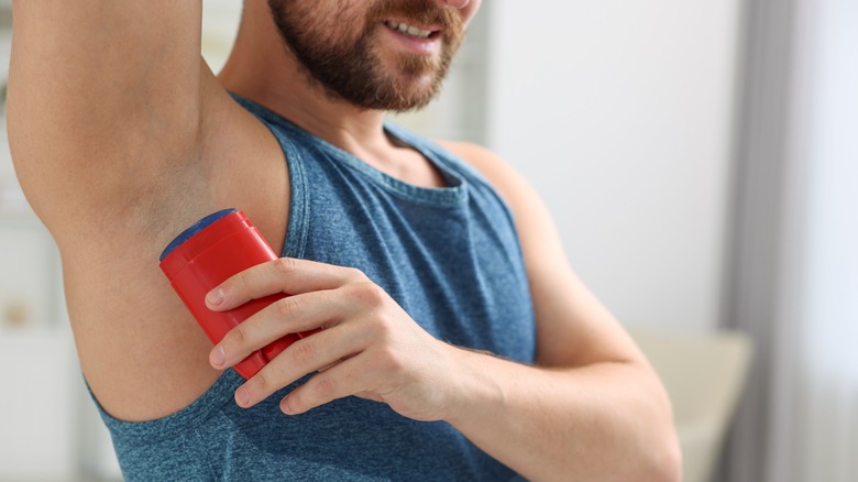 Person applying deodorant to armpit