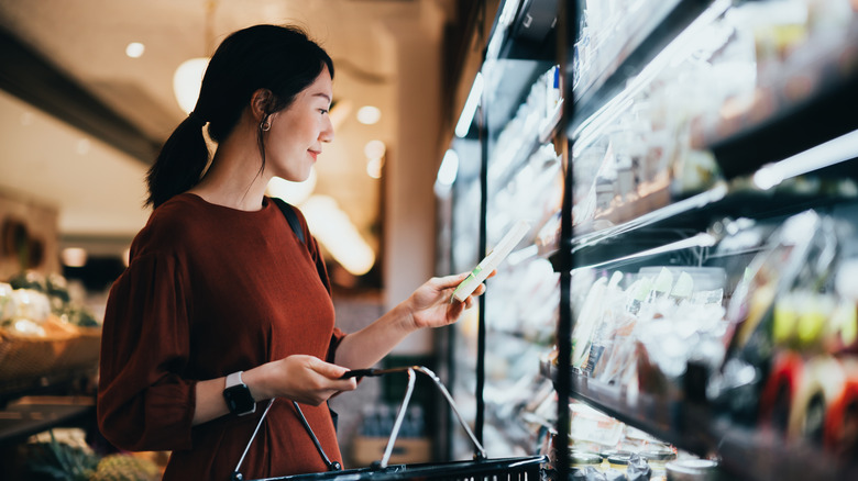 A woman looking at products at a refrigerated section of a convenience store