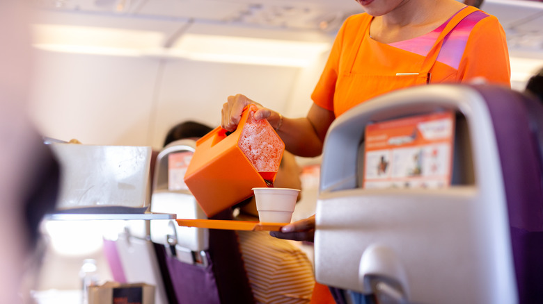 Flight attendant serving a drink on a flight