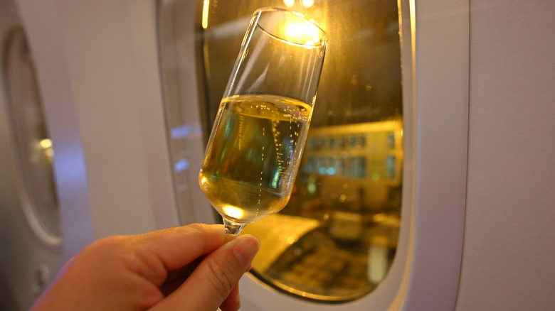 Holding up a glass of champagne to an airplane window