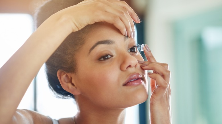 A woman putting in contact lenses.