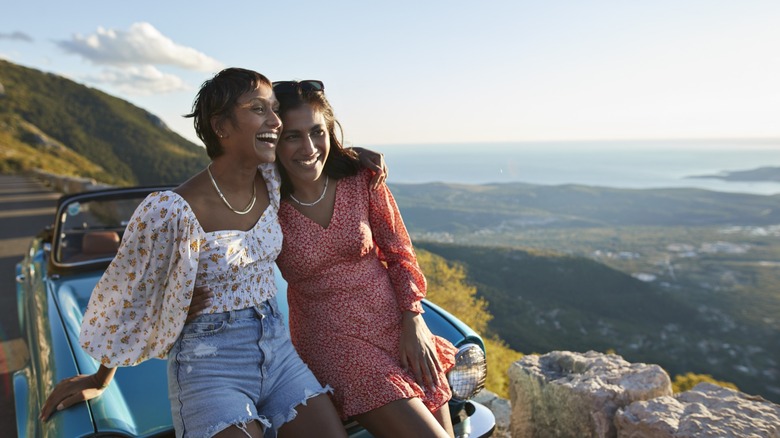 A pair of women pulled over on the side of the road in front of a convertible.