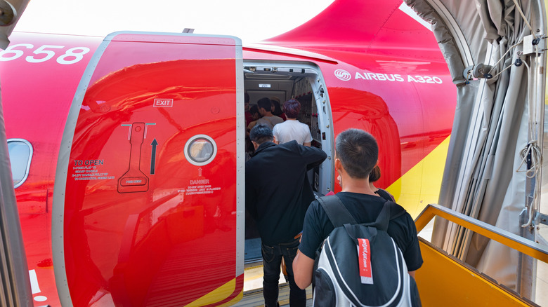 Passengers boarding a Vietjet red airplane