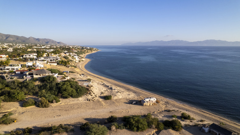 Beach, town, and sea with mountains in the background