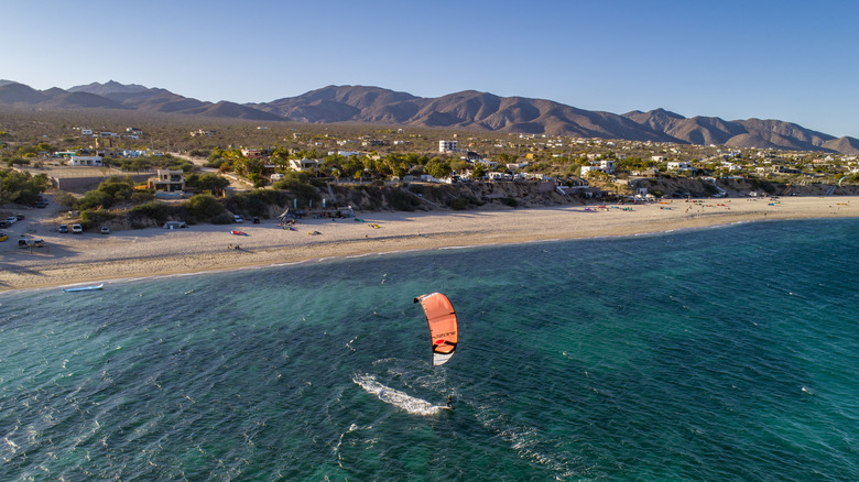 A kitesurfer surfing off the golden-sand beach of La Ventana, Baja California Sur, with mountains in the background