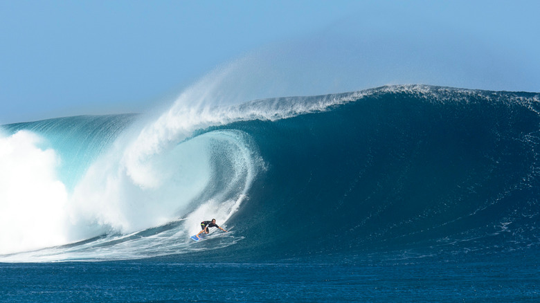 Surfer rides a large barreling wave at Cloudbreak in Fiji