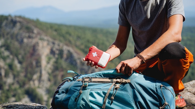 Man holding a first aid kit outside of a backpack