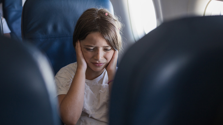 young girl covering ears flight