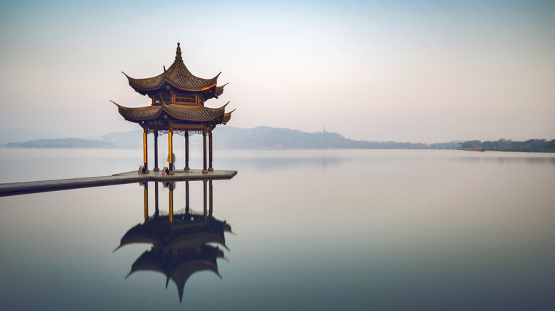 Tiered pavilion reflected in the waters of a misty lake