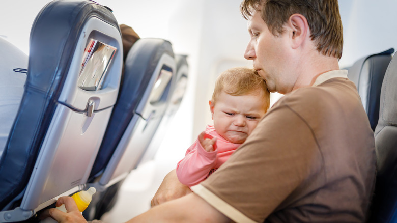 upset baby on father's lap on plane