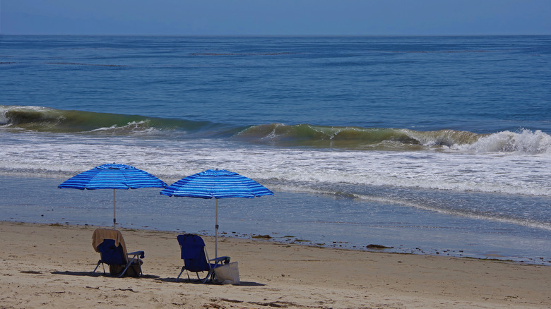 Two blue umbrellas and chairs on a beach