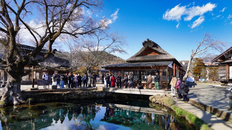 View of people around a pond and thatched building in Oshino Hakkai